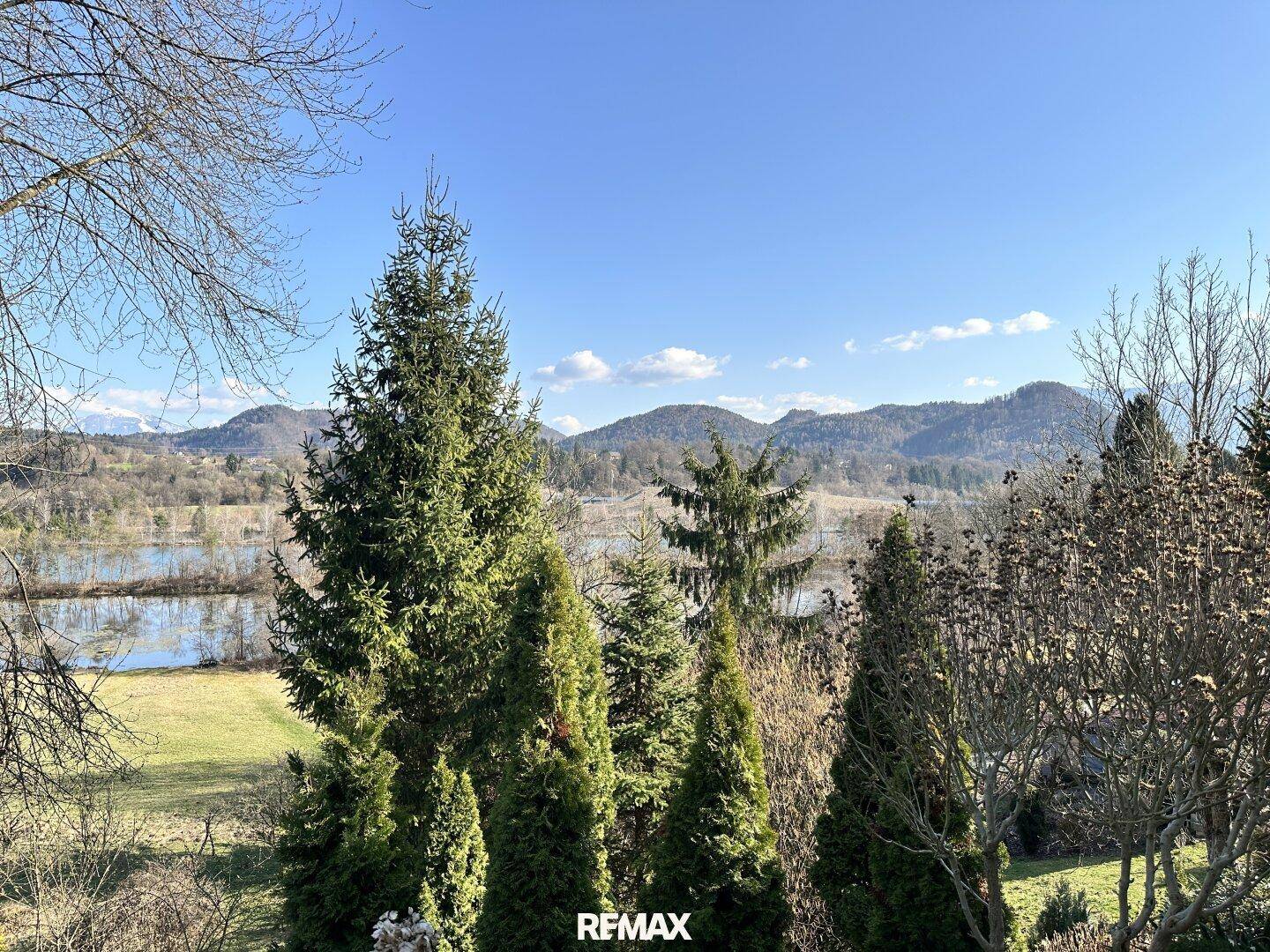 Panoramablick auf die umliegende Natur mit See, Bergen und üppiger Vegetation im Frühling.
