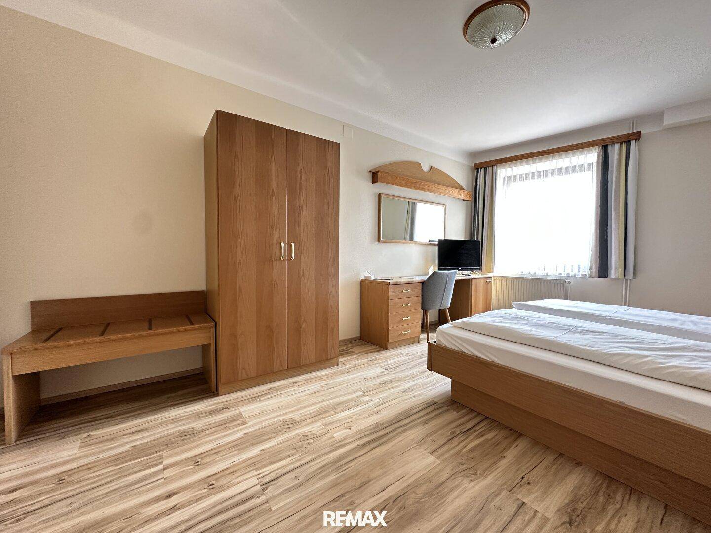 Geräumiges Schlafzimmer mit Doppelbett, großem Kleiderschrank und Laminatboden.