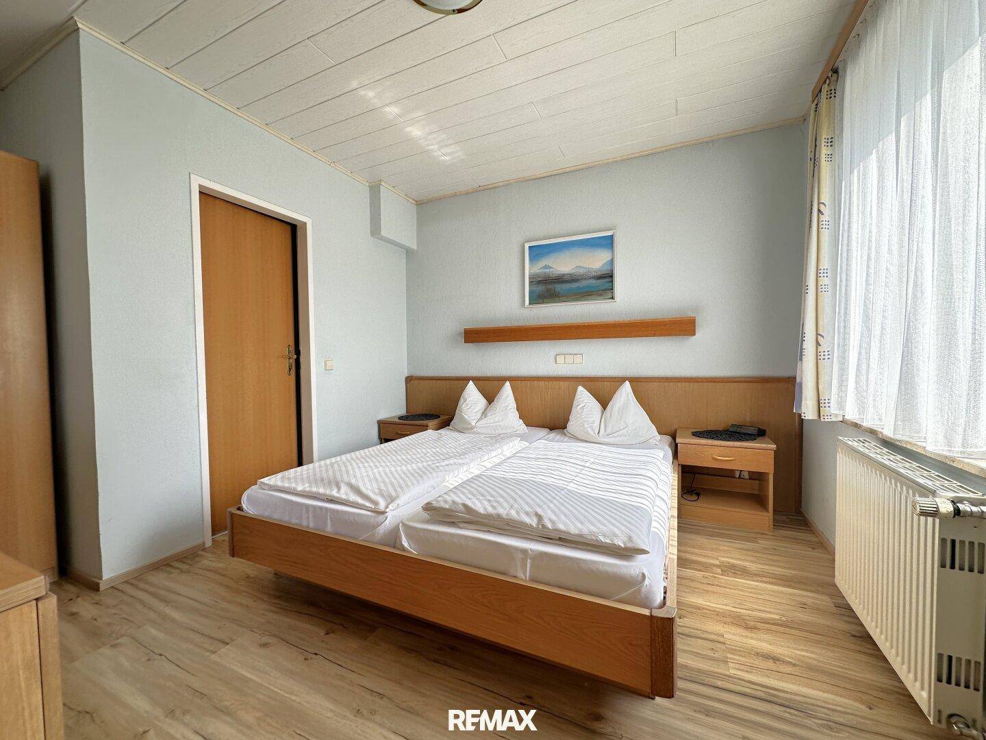 Gemütliches Schlafzimmer mit Doppelbett, Holzmöbeln und Laminatboden.