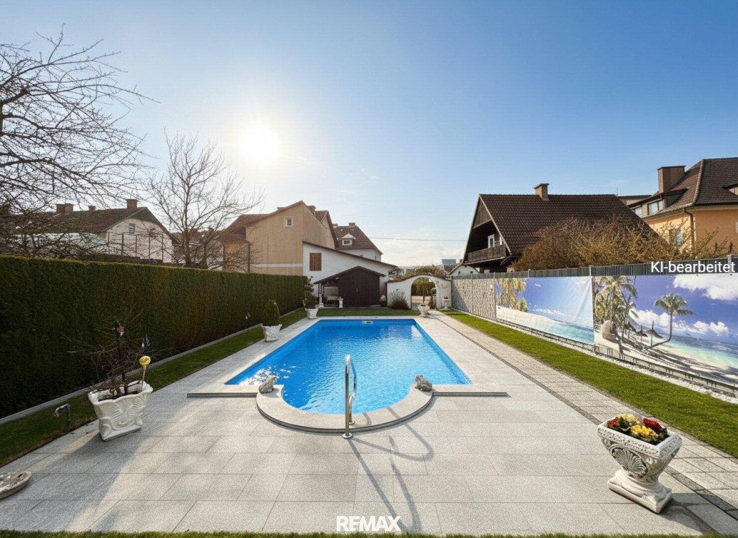 Einladender Poolbereich mit gepflasterter Umrandung, Rasenflächen und einer Hecke im Hintergrund.