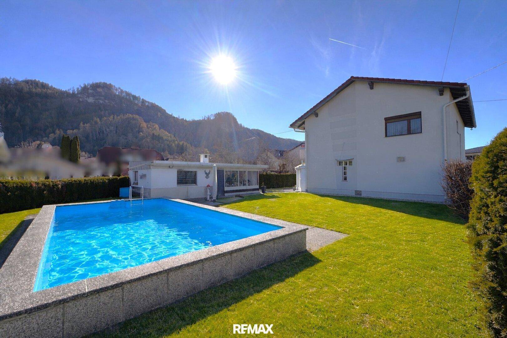 Sonniger Gartenbereich mit Pool und Blick auf die umliegende Berglandschaft.