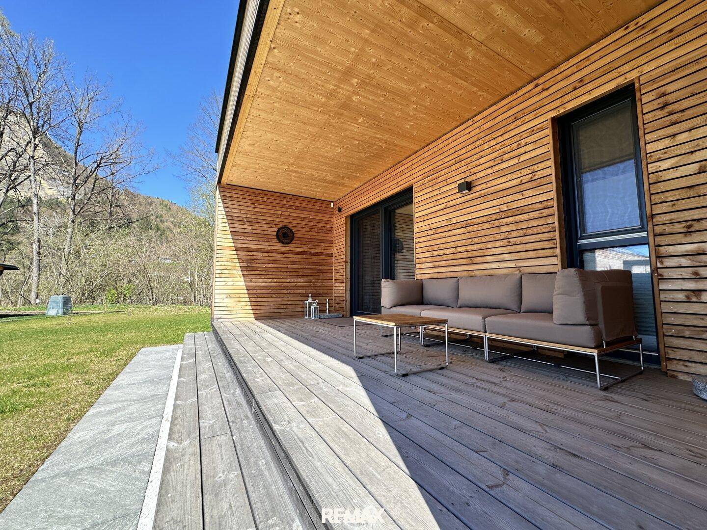 Geräumige Holzterrasse mit bequemen Outdoor-Möbeln und Blick auf die umliegende Natur.