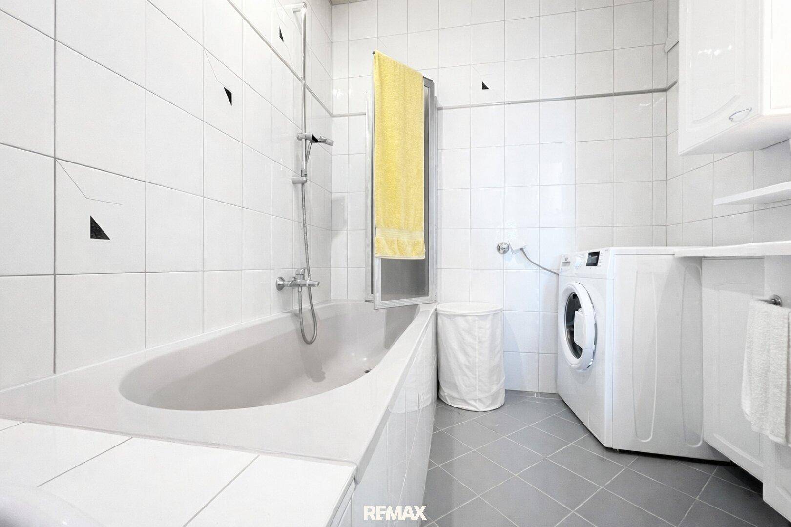 Funktionales Badezimmer mit Badewanne, Dusche und Waschmaschine.