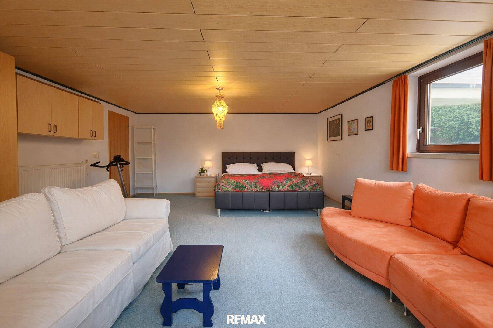 Geräumiges Schlafzimmer im Untergeschoss mit Teppichboden, Doppelbett und Sofa.