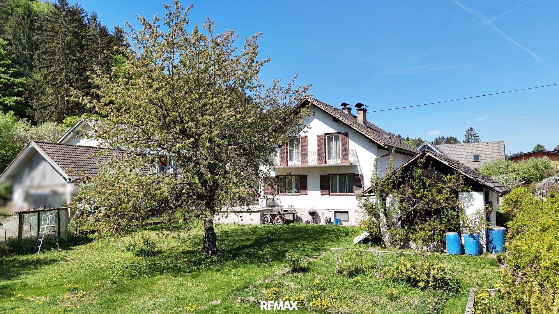 Ansicht des Hauses vom Garten aus mit blühendem Baum und Nebengebäude.