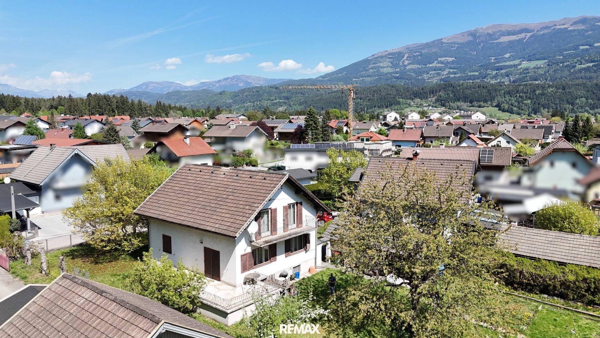 Weitläufige Ansicht der Wohnsiedlung mit Bergen im Hintergrund unter blauem Himmel.