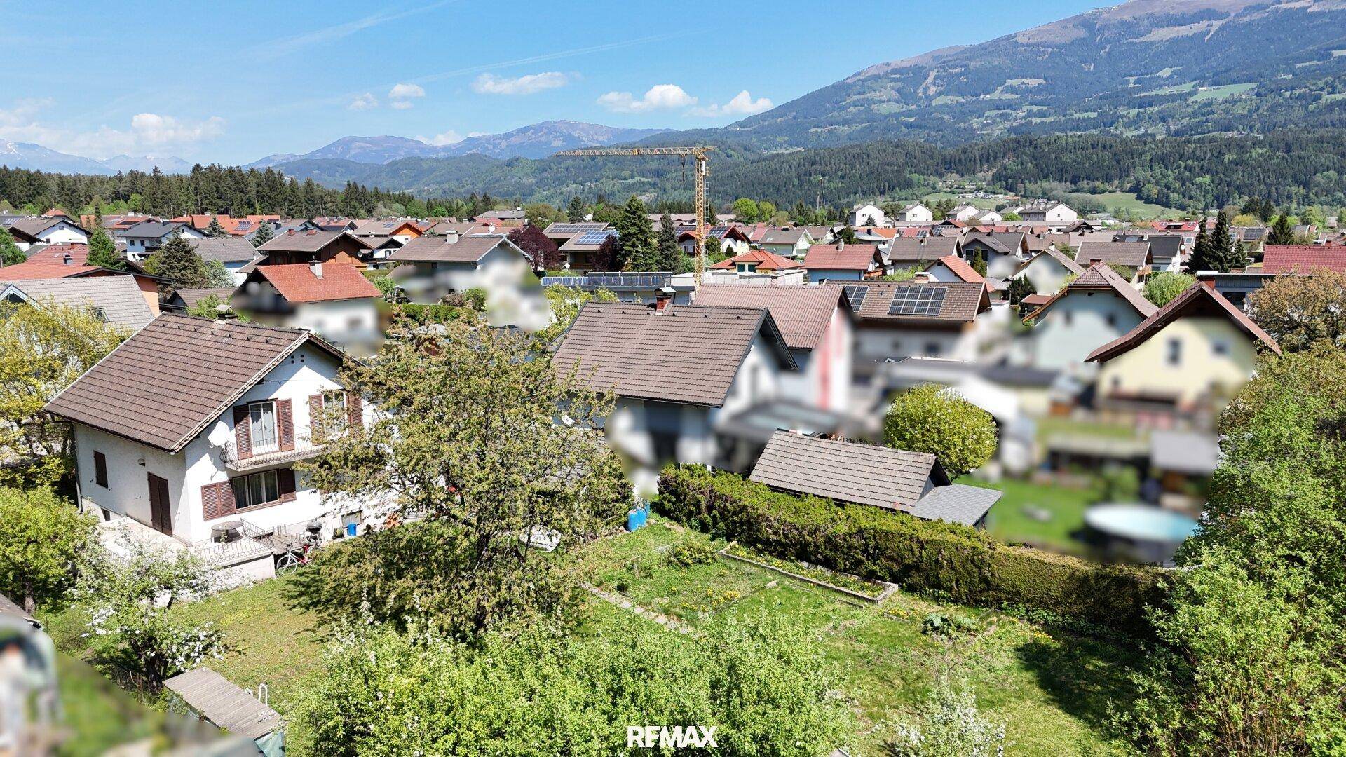 Weitläufige Ansicht der Wohnsiedlung mit Bergen im Hintergrund unter blauem Himmel.