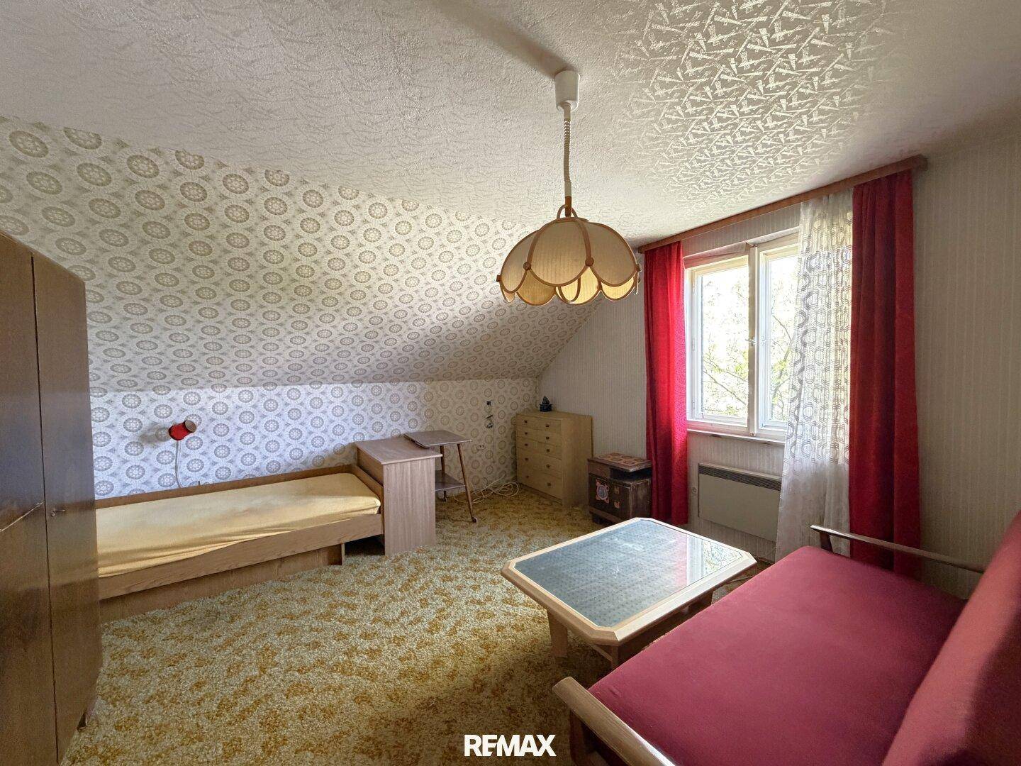 Schlafzimmer im Dachgeschoss mit gemusterter Tapete, Teppichboden und Einzelbett.