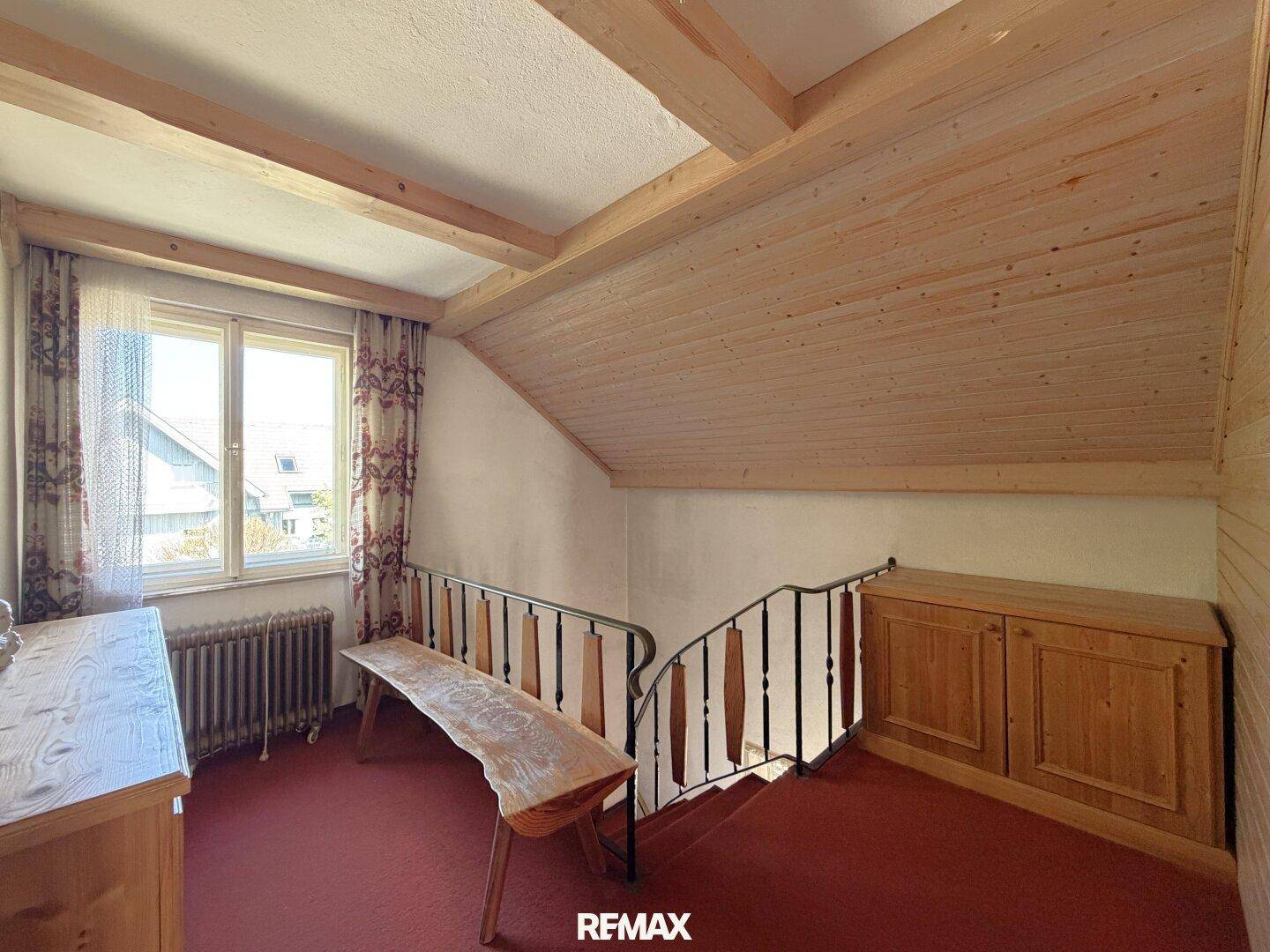 Flurbereich im Obergeschoss mit Holzverkleidung, Fenster und Treppengeländer.