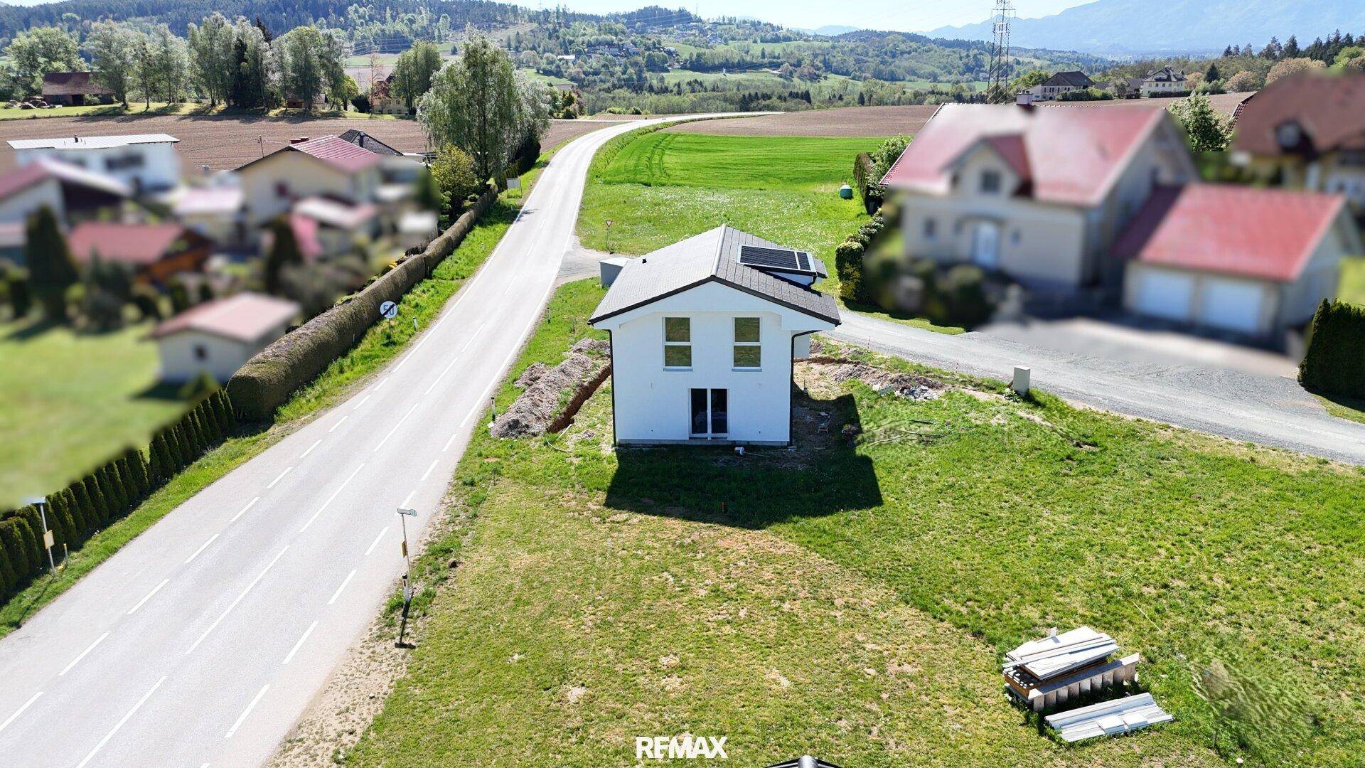 Weitläufige Luftaufnahme des Neubaus in einer idyllischen ländlichen Umgebung mit weiten Feldern.