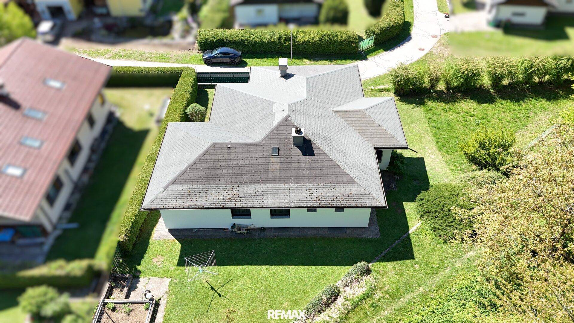 Rückansicht des Hauses mit Garten und Wäscheleine, umgeben von Hecken und Bäumen.