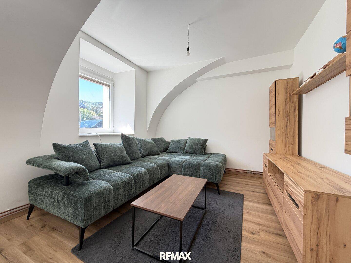 Gemütliches Wohnzimmer mit großem Ecksofa, Holzboden und interessanter Dachschräge.