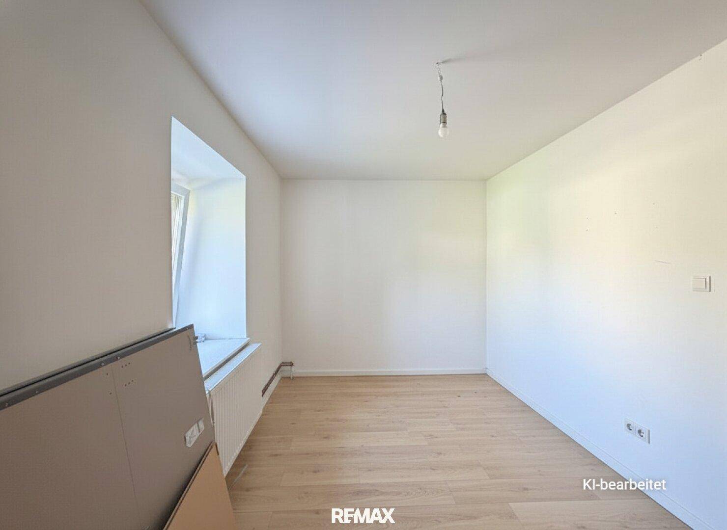 Leerer Raum mit hellem Holzboden und Fenster, bereit zur individuellen Gestaltung.