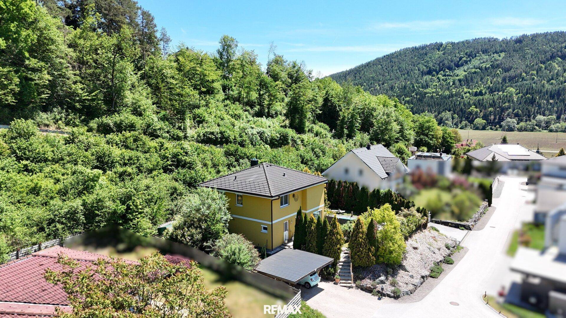 Weitläufige Ansicht des Hauses in ländlicher Umgebung mit grünen Hügeln und klarem Himmel.