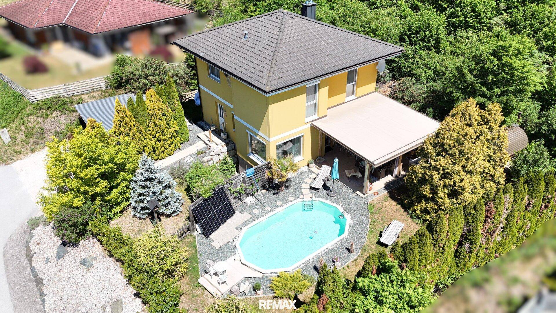 Luftaufnahme des Hauses mit Pool, überdachter Terrasse und Solarpaneelen, umgeben von Bäumen.
