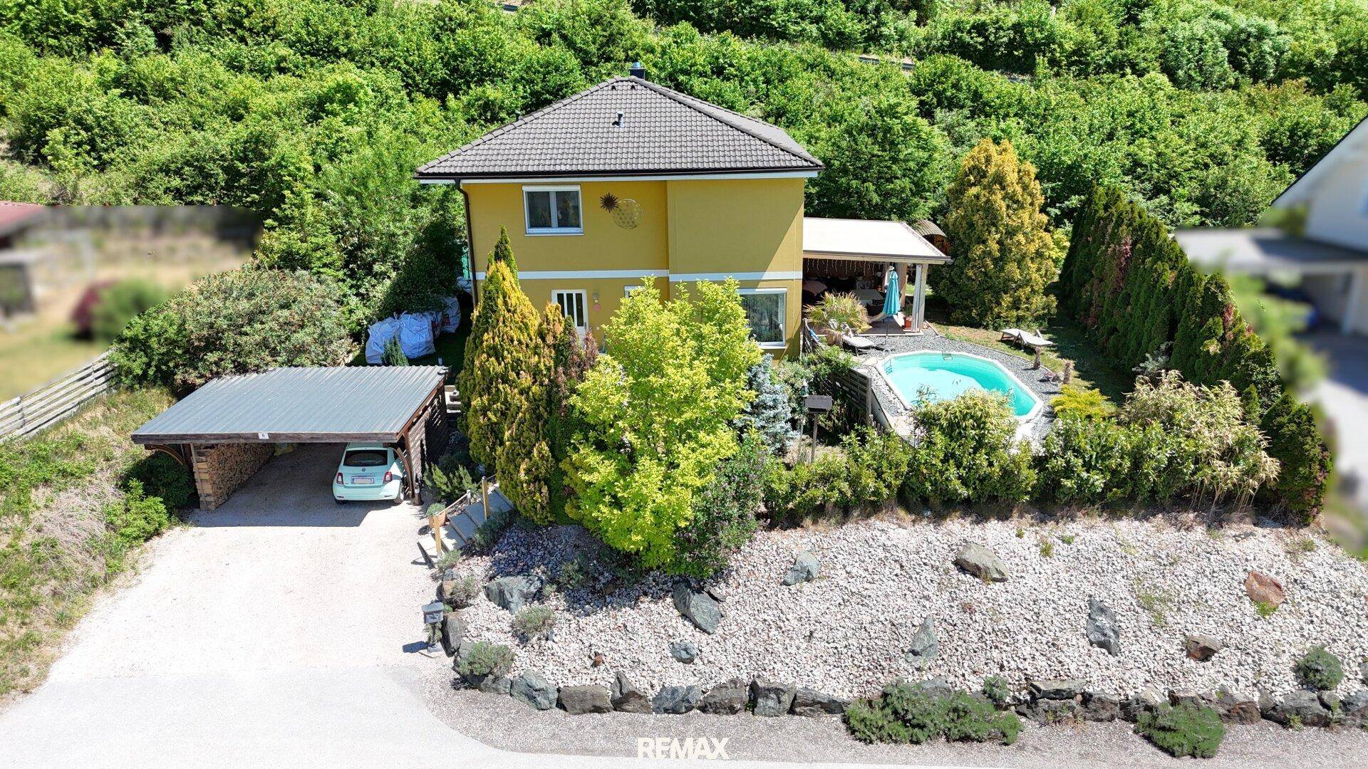Gesamtansicht des Hauses mit Pool, Carport und gepflegtem Garten, eingebettet in die Natur.