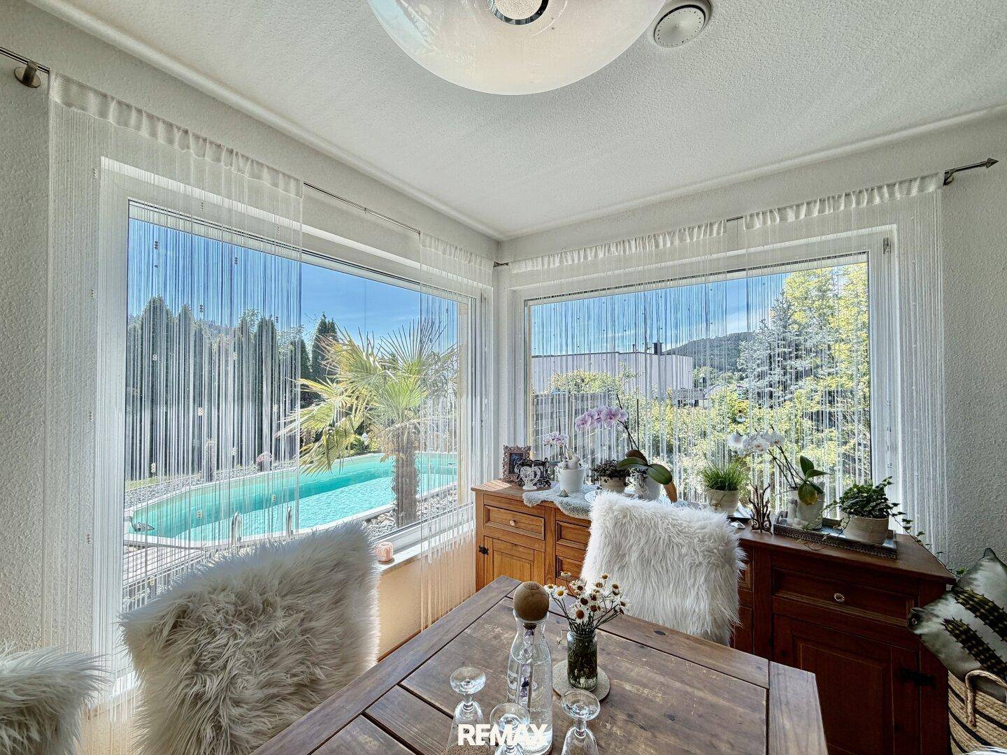 Esszimmer mit großen Fenstern, die einen direkten Blick auf den Pool und den Garten bieten.