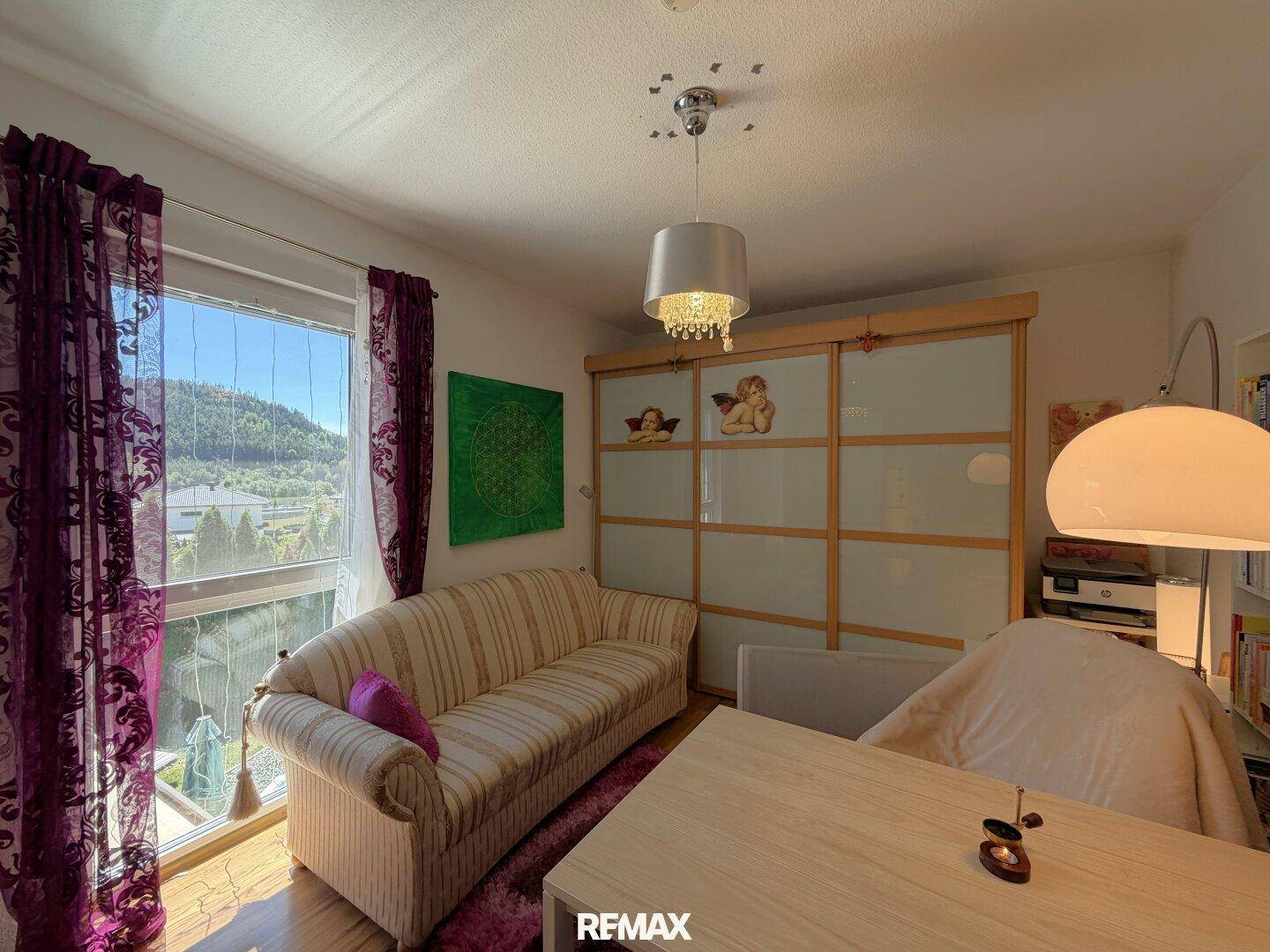 Helles Zimmer mit Sofa, Schiebetüren und weitem Blick auf die grüne Landschaft.