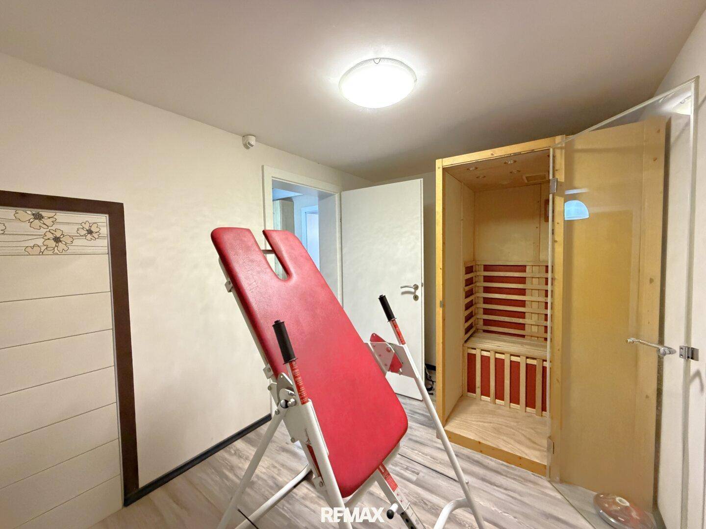 Raum mit Infrarotsauna und Fitnessgerät, ideal für Wellness und Sport.