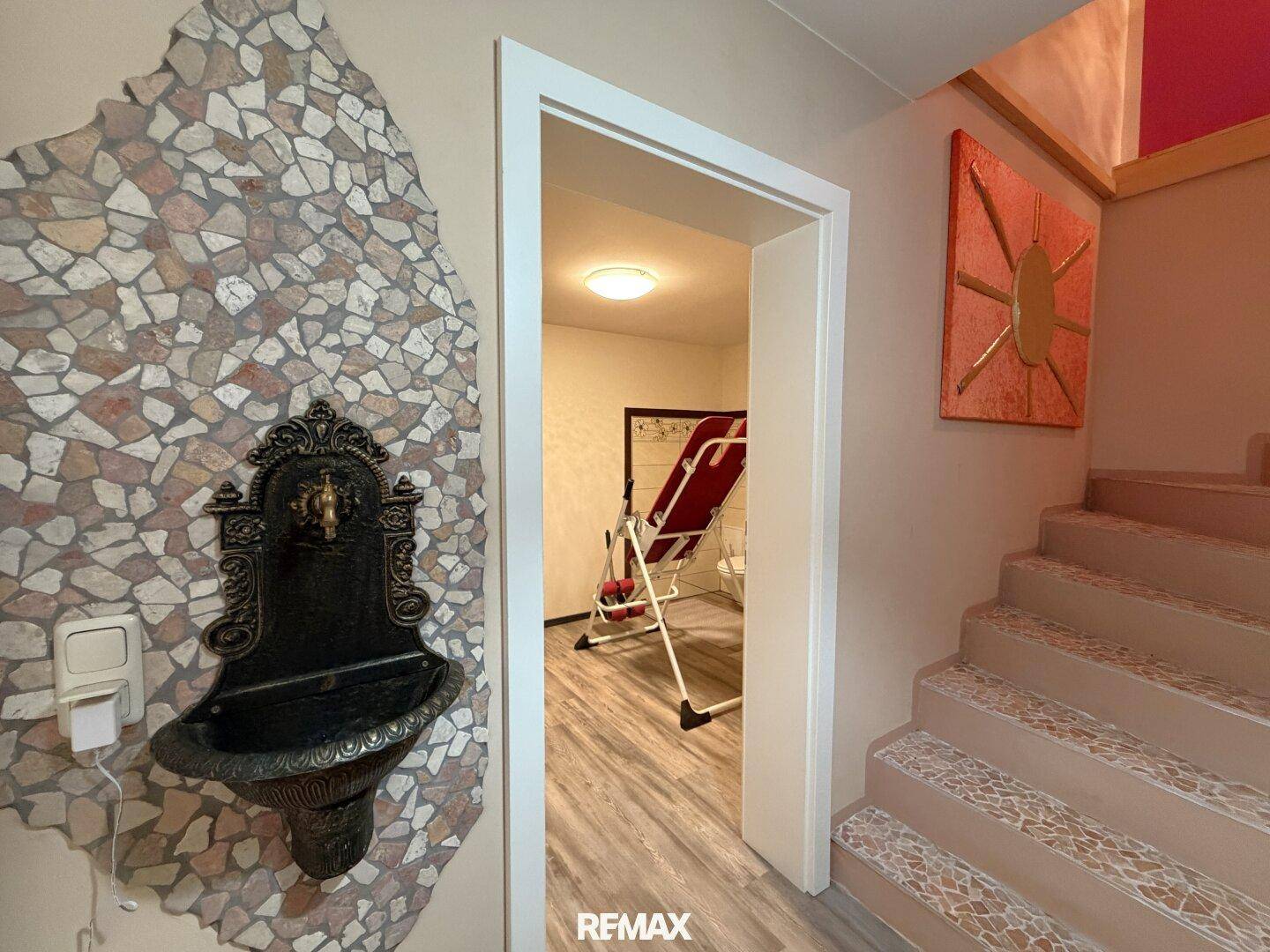Flur mit dekorativem Wandbrunnen und Treppe, die zu weiteren Räumen führt.