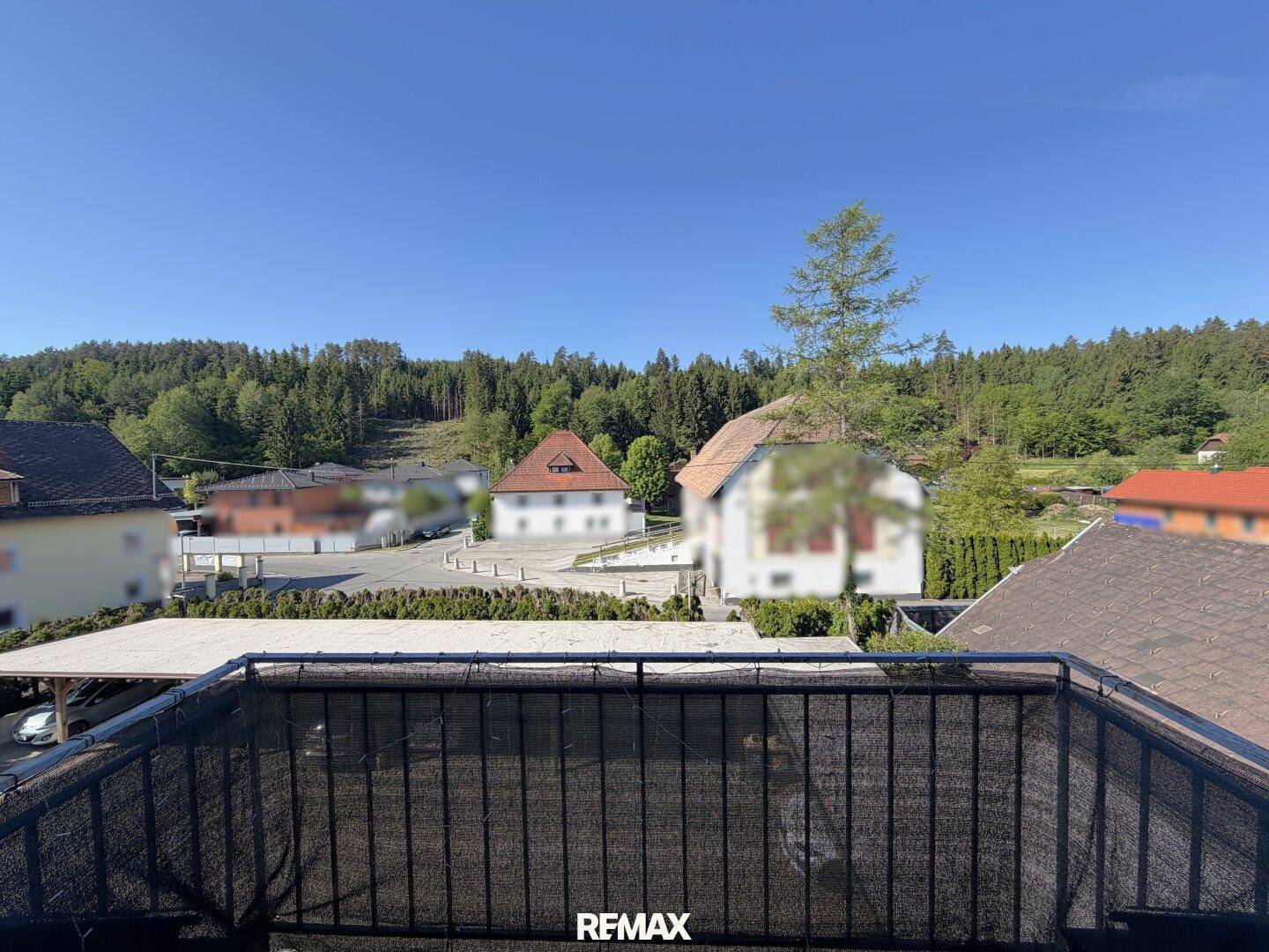 Balkon mit Blick auf die umliegende Wohngegend und bewaldete Hügel.