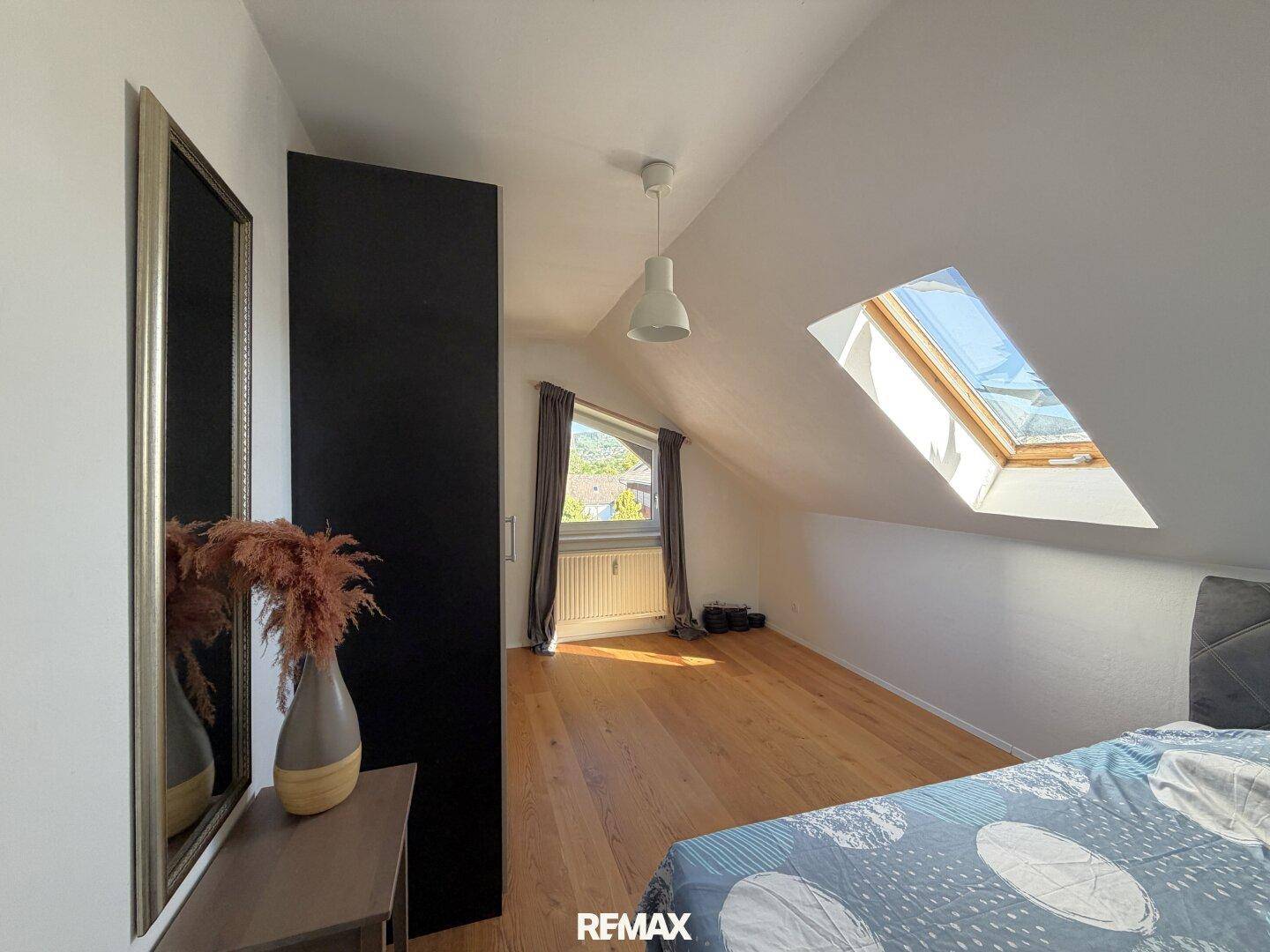 Schlafzimmer im Dachgeschoss mit Holzboden, Dachfenster und viel Tageslicht.
