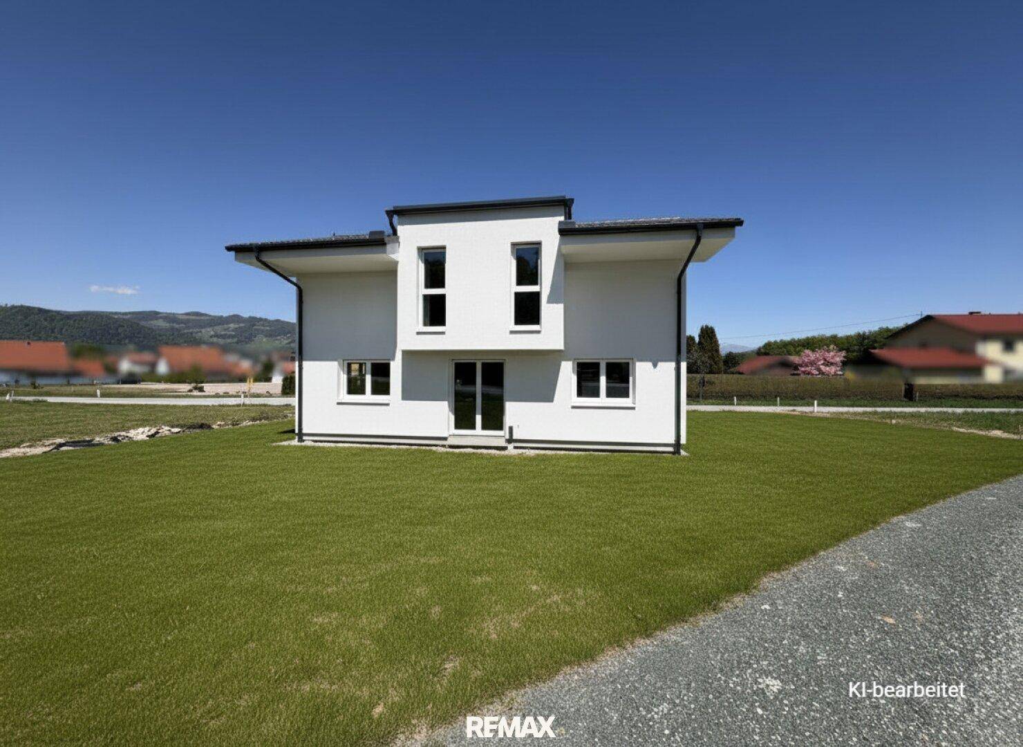 Vorderansicht des modernen Einfamilienhauses mit gepflegtem Rasen unter blauem Himmel.