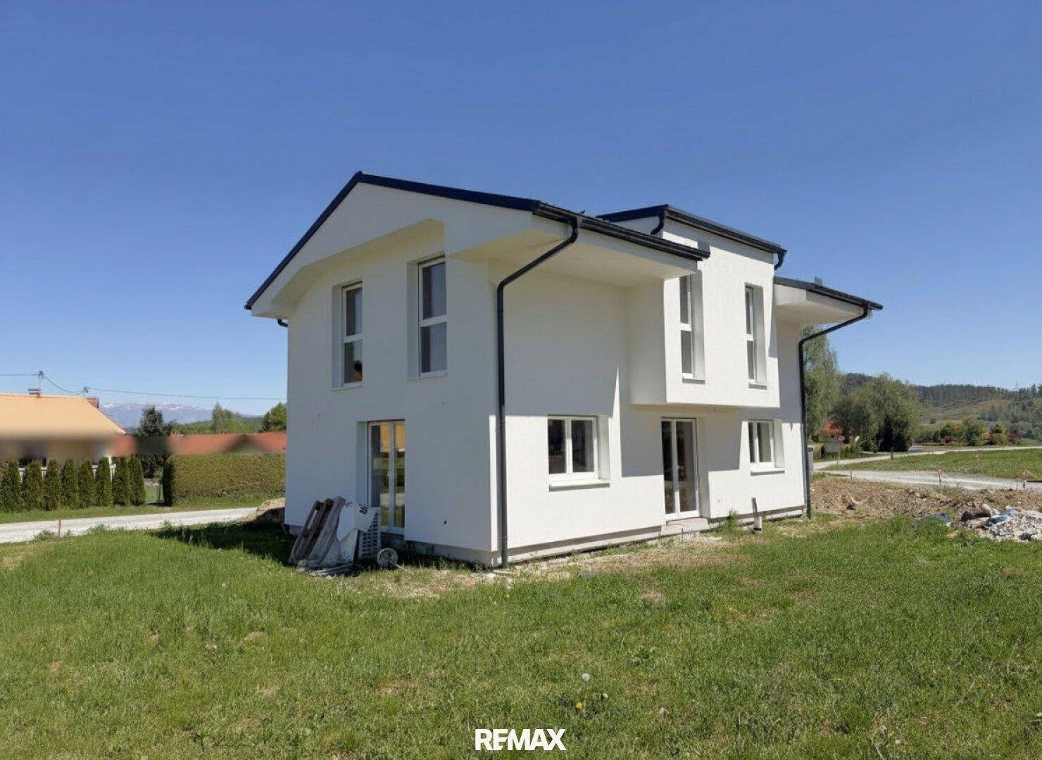 Seitenansicht des modernen Einfamilienhauses mit weißer Fassade und dunklem Satteldach.