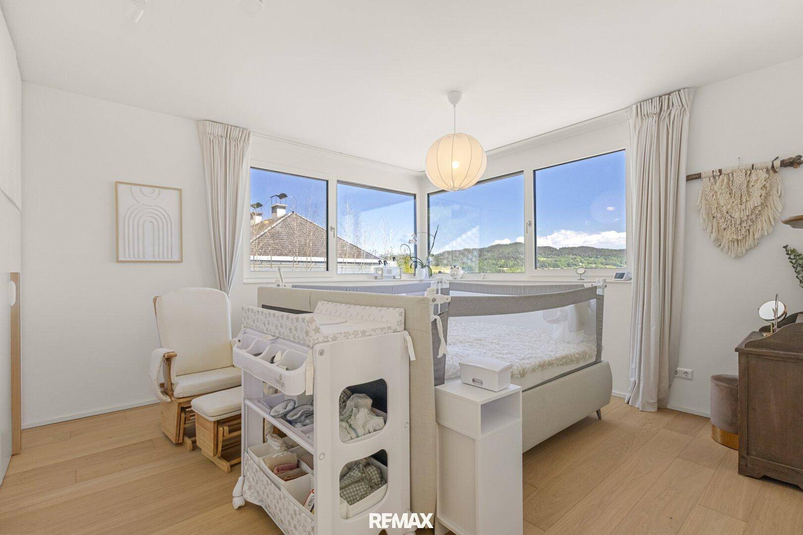 Helles Kinderzimmer mit großen Fenstern und Blick auf die Umgebung.
