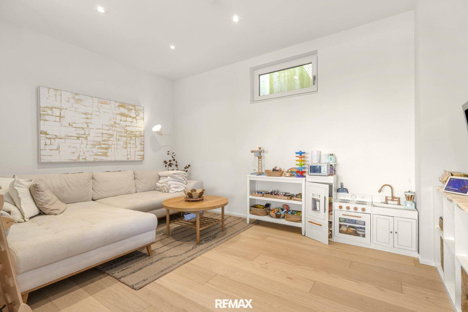 Helles Wohnzimmer mit bequemer Couch und einem Bereich für Kinderspielzeug.