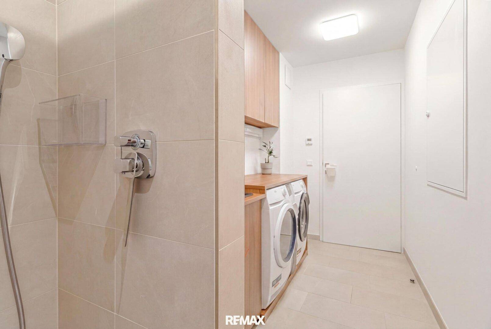 Praktischer Hauswirtschaftsraum mit Waschmaschine, Trockner und integrierter Dusche.