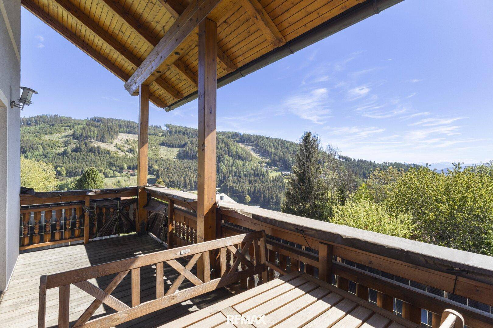 Geräumiger Holzbalkon mit atemberaubendem Blick auf die umliegende Berglandschaft.