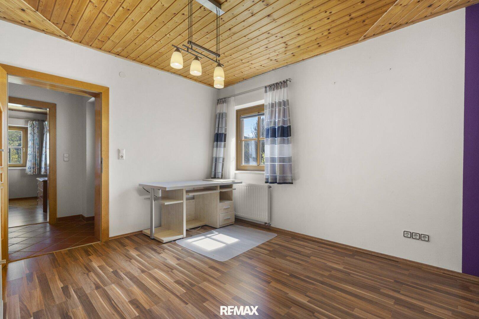 Helles Zimmer mit Holzboden, Fenster und Blick ins Grüne, ideal als Büro oder Gästezimmer.