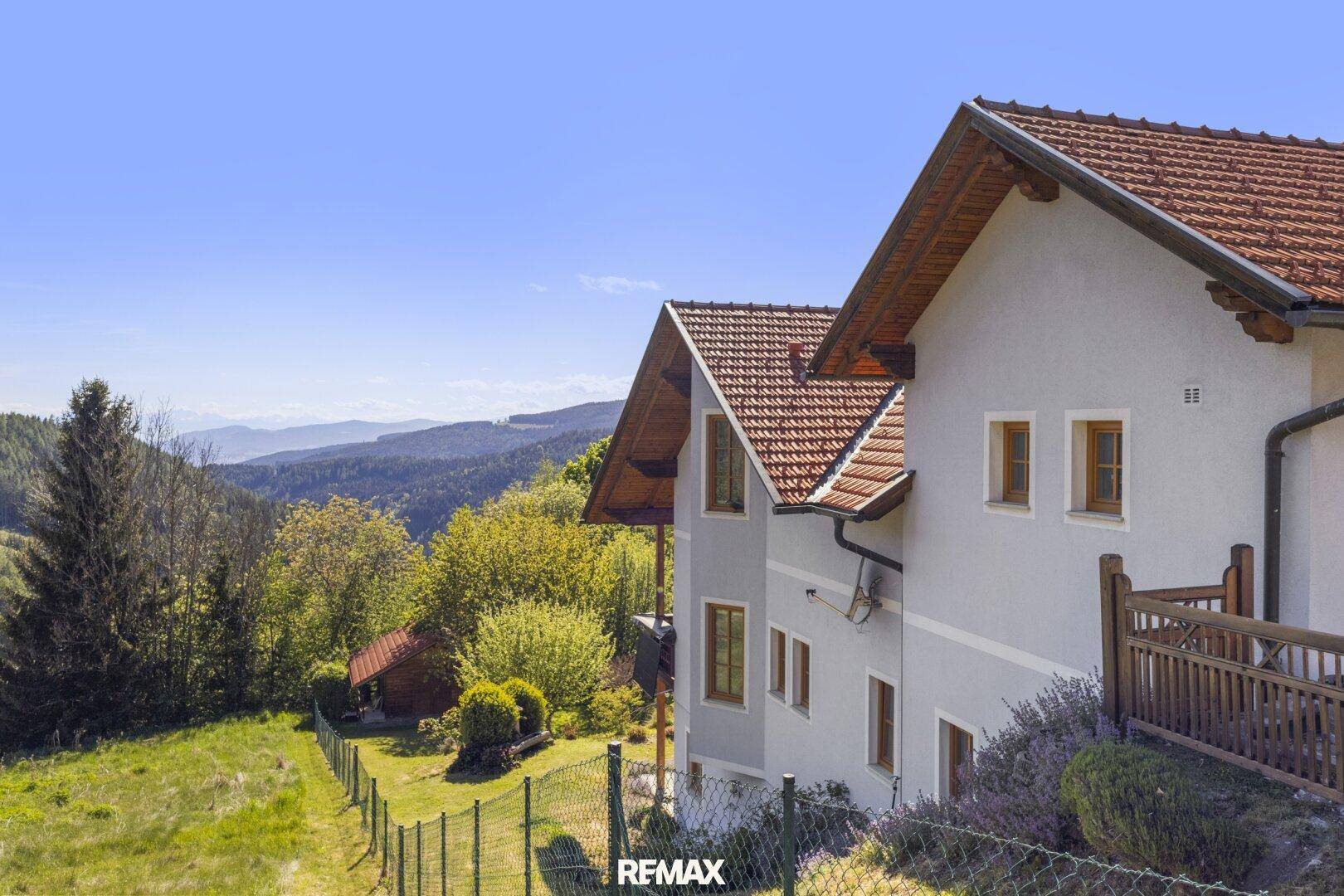 Seitenansicht des Hauses mit weitem Blick auf die Berglandschaft und grüne Natur.