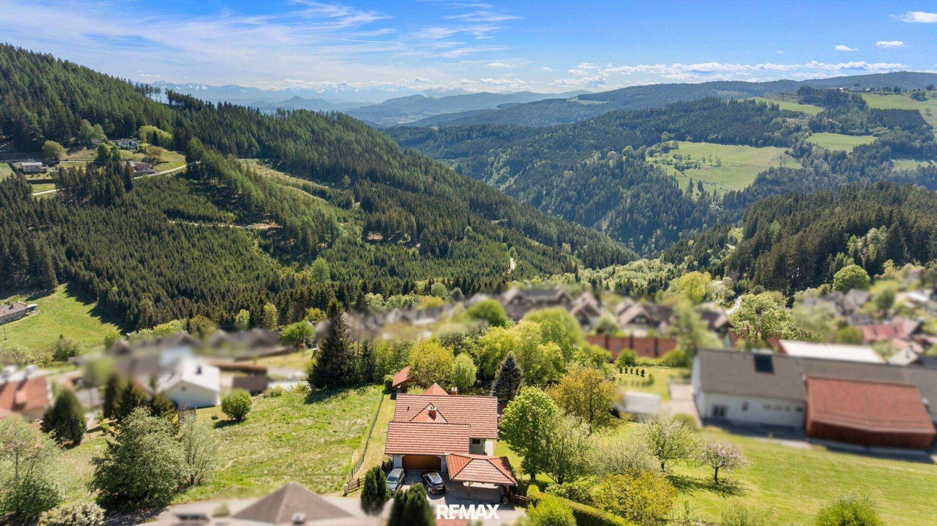 Panoramablick auf das Anwesen inmitten einer idyllischen Berg- und Waldlandschaft.