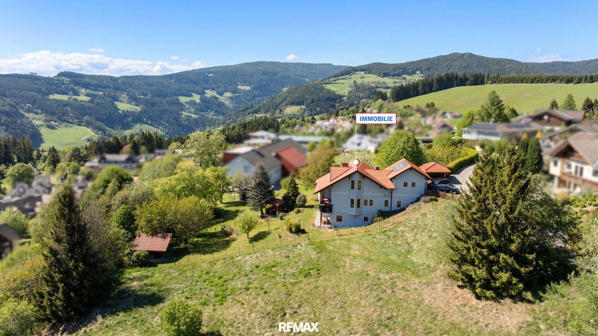 Luftaufnahme des Hauses mit Markierung, eingebettet in die grüne Hügellandschaft.