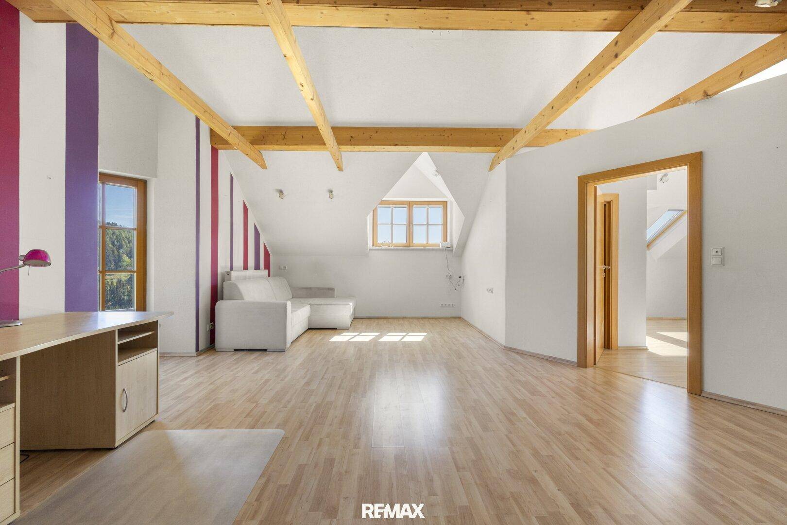Großer offener Dachbodenraum mit sichtbaren Holzbalken, Dachschrägen und Laminatboden.