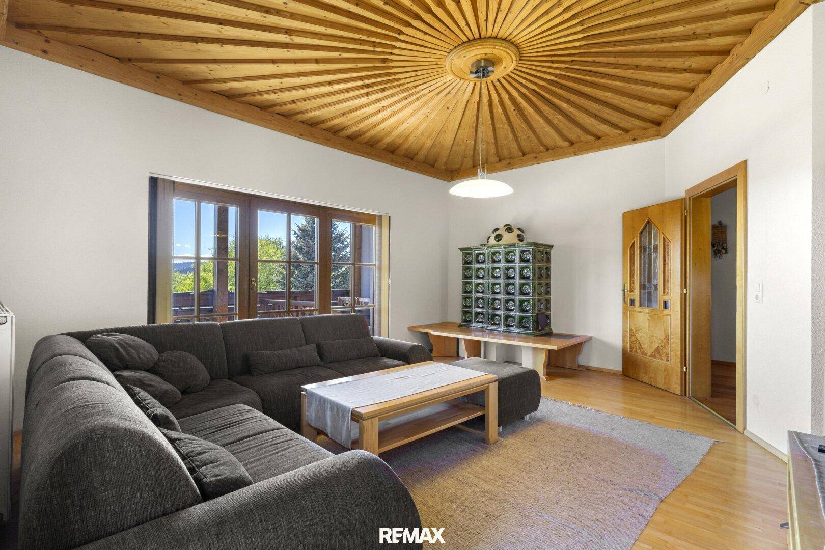 Wohnzimmer mit Kachelofen, Holzboden und traditioneller Einrichtung.