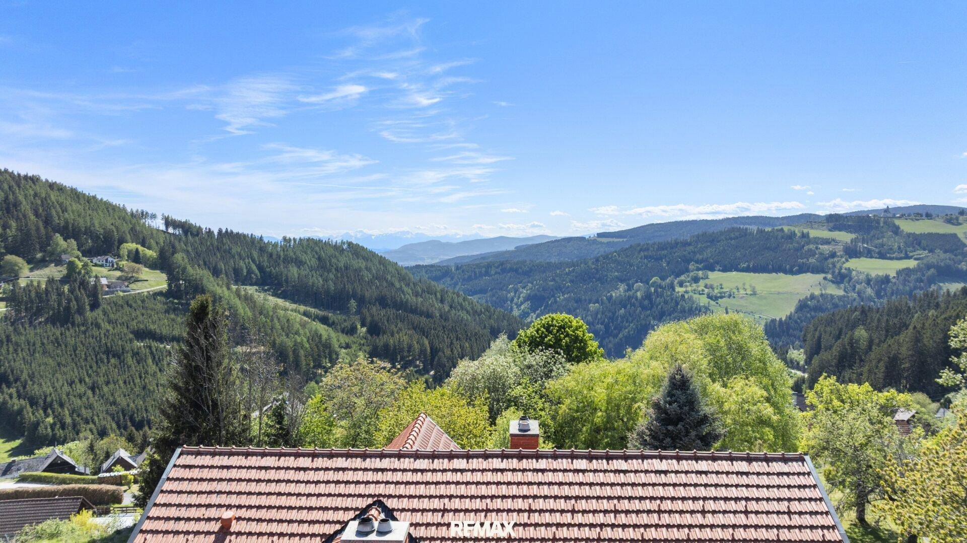 Atemberaubender Panoramablick über bewaldete Hügel und Täler unter blauem Himmel.