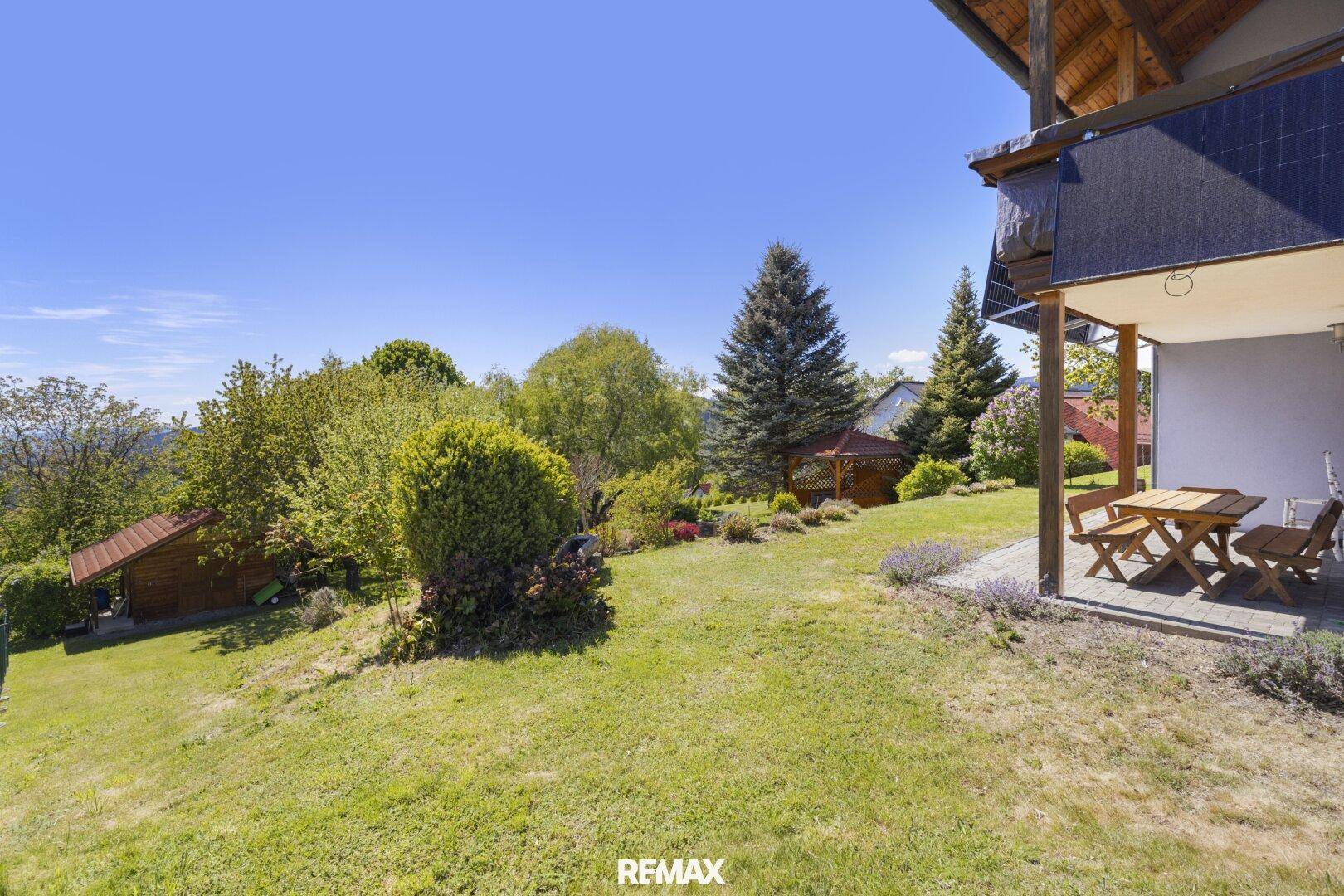 Gepflegter Gartenbereich mit überdachter Terrasse und Sitzgelegenheiten, umgeben von viel Grün.