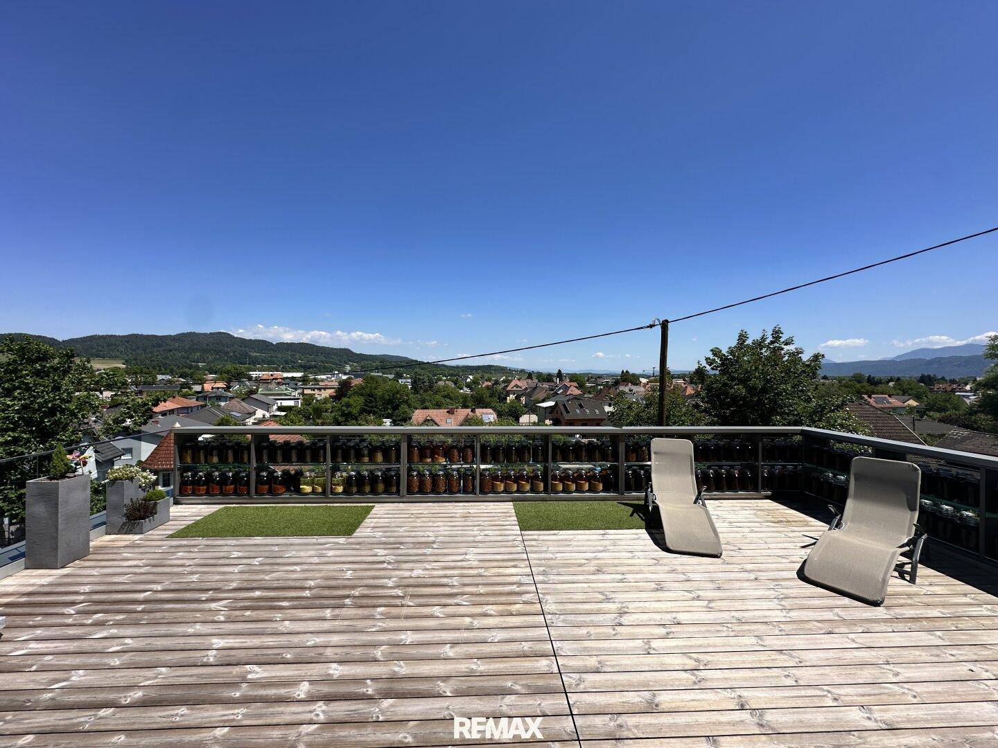Weitläufige Holzterrasse mit Liegestühlen und einem beeindruckenden Panoramablick.