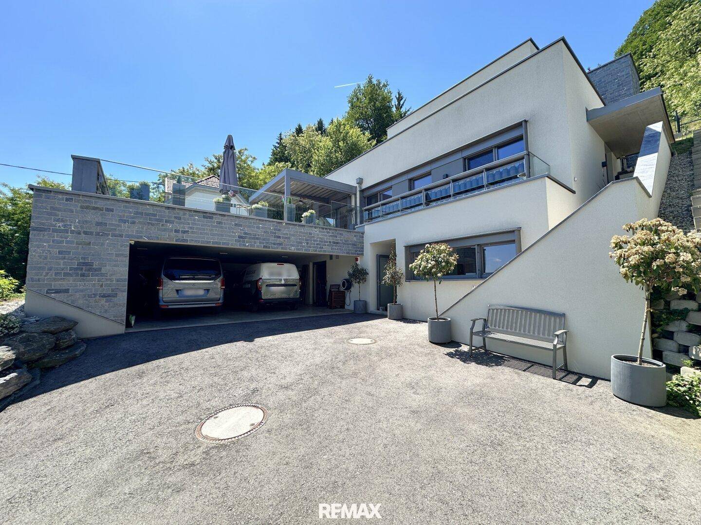 Moderne Architektur des Hauses mit integrierter Doppelgarage und großzügiger Auffahrt im Freien.