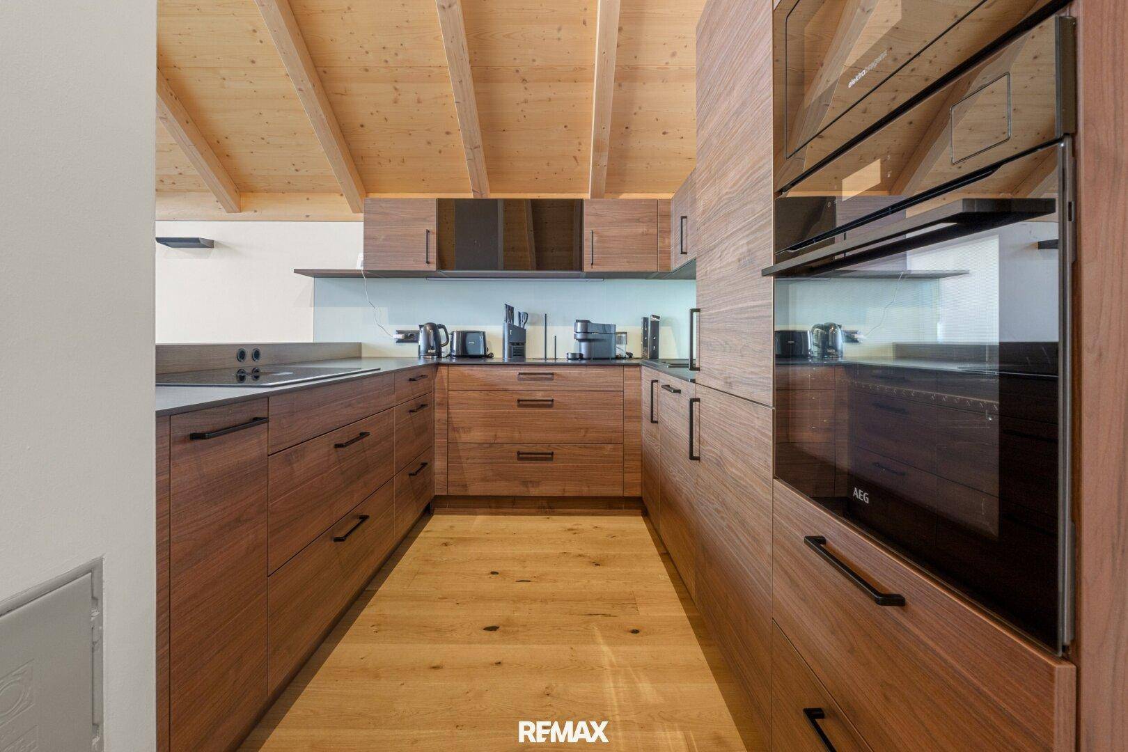 Moderne Einbauküche mit Holzfronten, integrierten Geräten und viel Stauraum.
