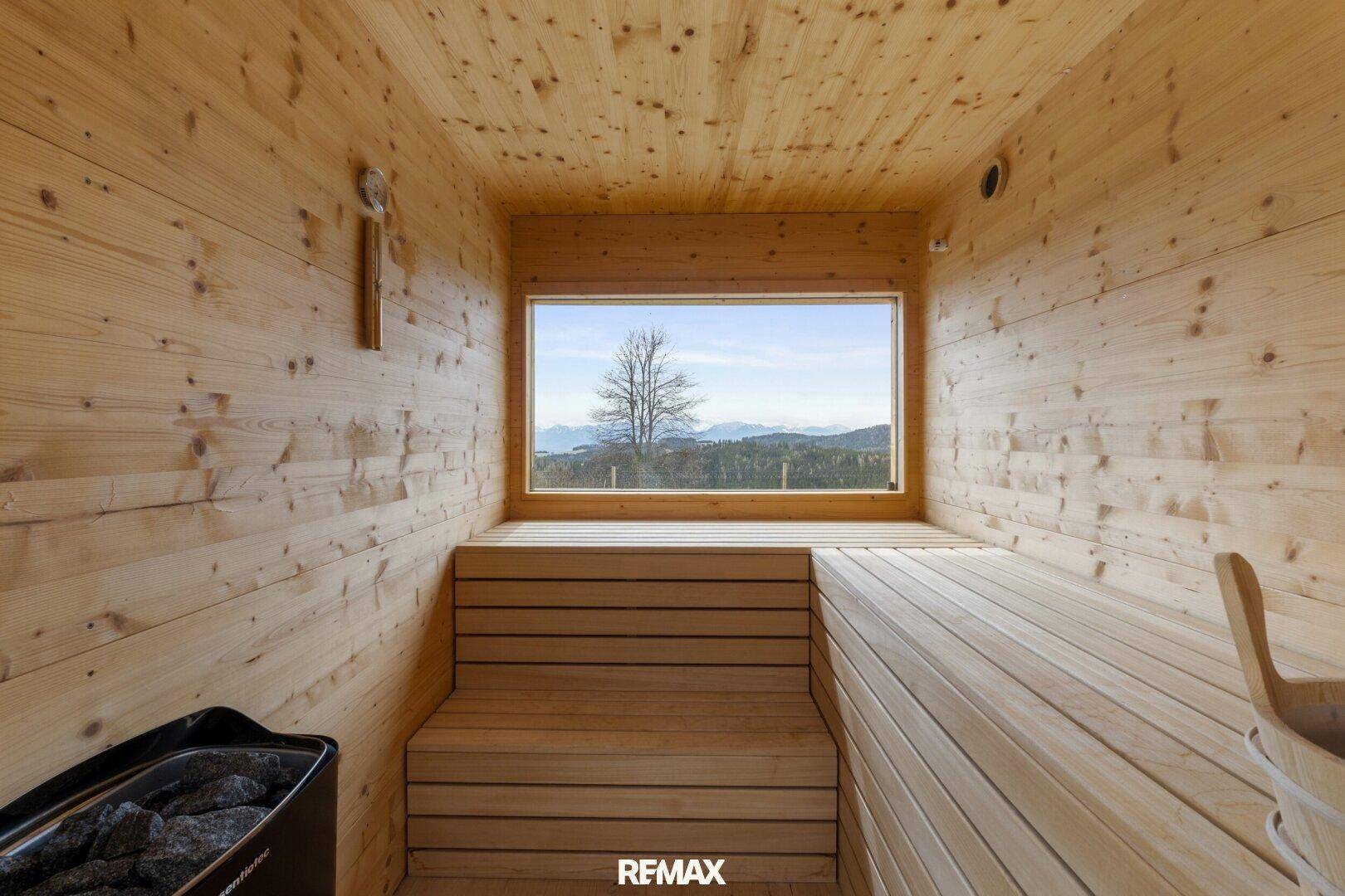 Gemütliche Holzsauna mit Panoramablick durch ein großes Fenster in die Natur.