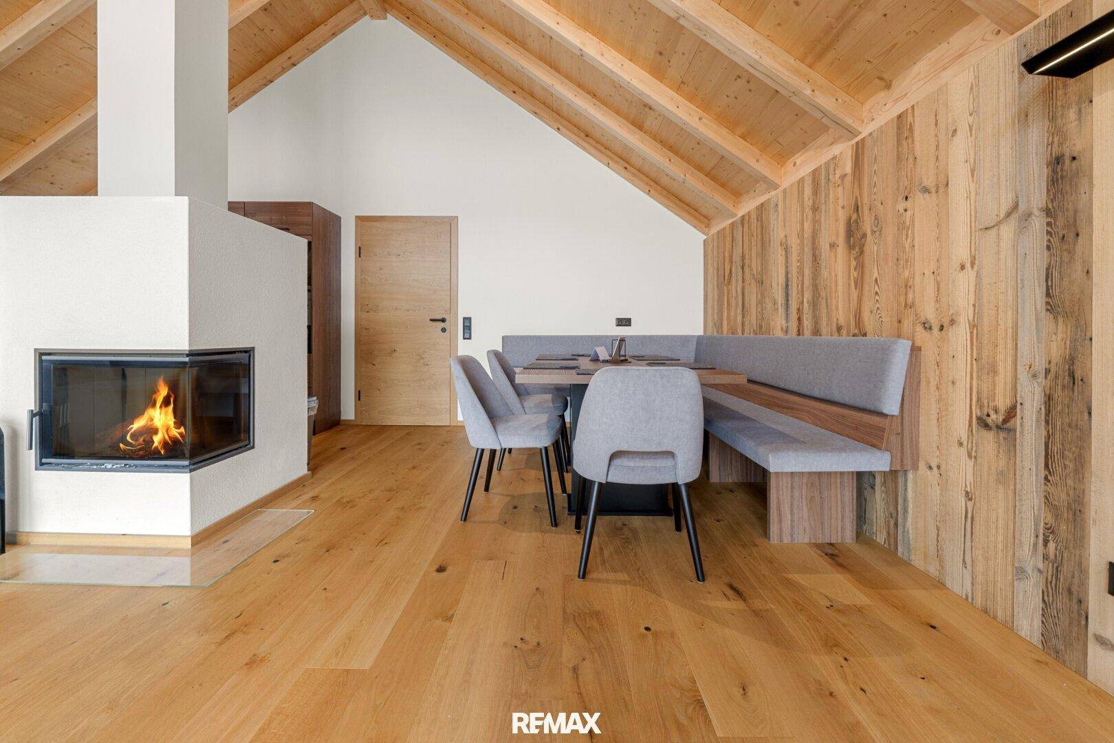Gemütlicher Essbereich mit Kamin, Holzwänden und einer integrierten Sitzbank für gesellige Runden.
