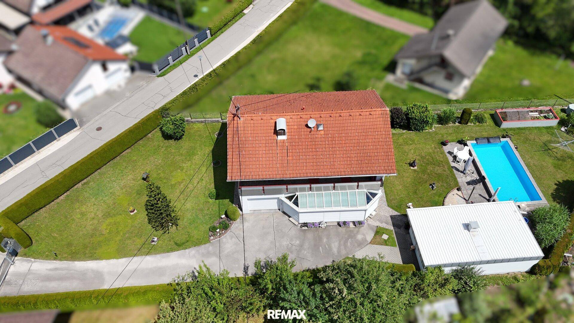 Vogelperspektive des Anwesens mit Haus, Wintergarten, Pool und Gartenbereich.