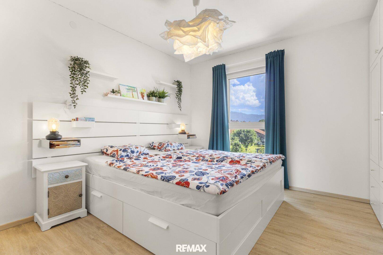 Helles Schlafzimmer mit Doppelbett, Einbauschränken und Blick ins Grüne.