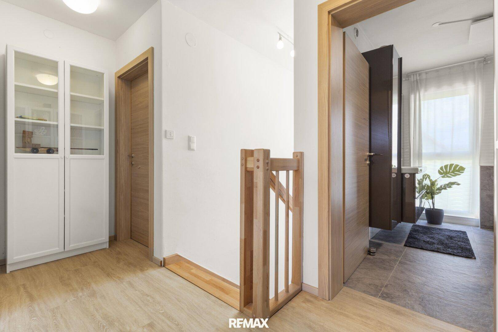 Heller Flur im Obergeschoss mit Laminatboden und Holzgeländer zur Treppe.