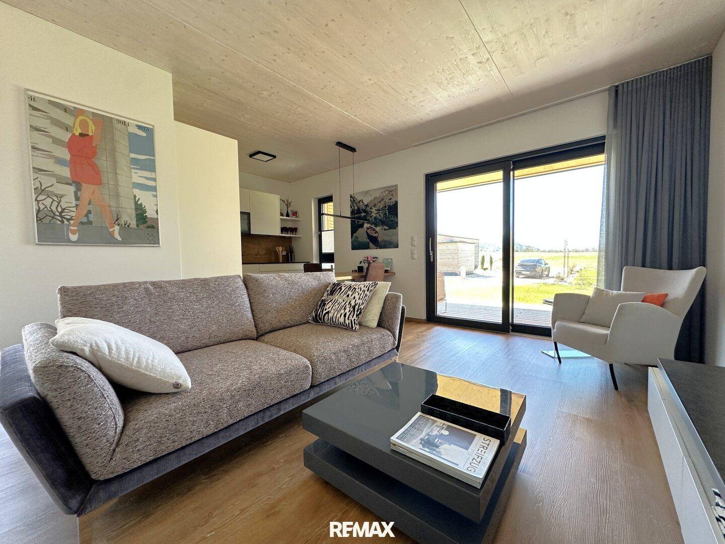 Helles Wohnzimmer mit bequemer Couch, Couchtisch und Zugang zur Terrasse durch große Fenster.