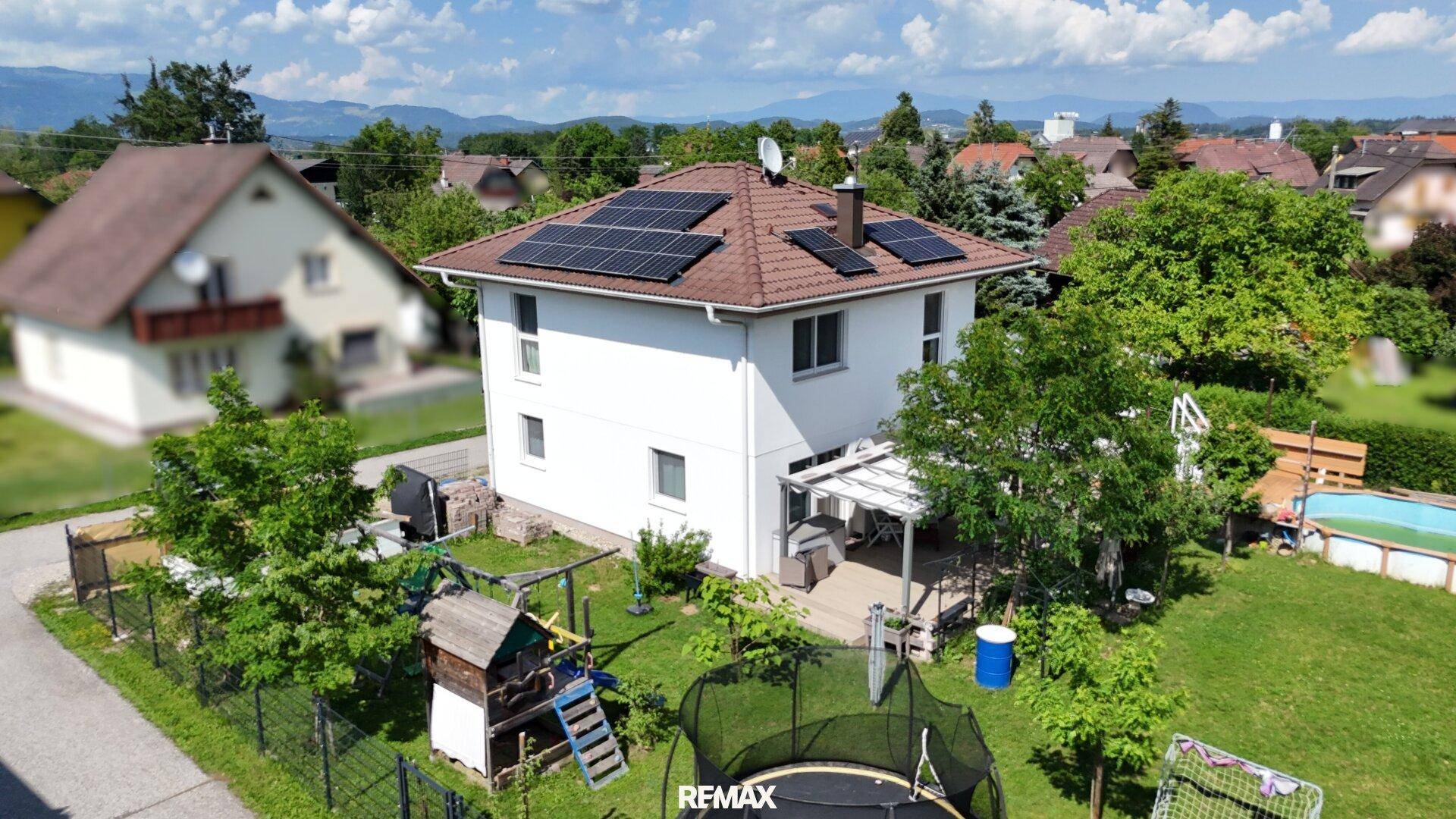 Weitläufiger Gartenbereich mit Spielgeräten, Trampolin und Pool neben dem Einfamilienhaus.